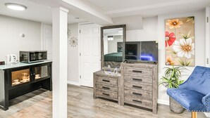 Ein modernes Wohnzimmer mit einem Holzkabinett, einem blauen Sessel und einem großen Blumenbild an der Wand.