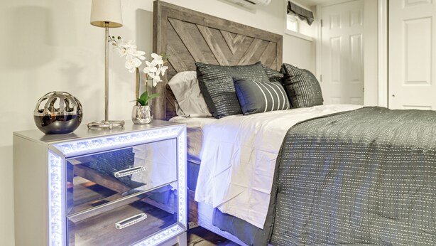Ein Schlafzimmer mit einem Bett, Nachttischen, einer Lampe, einer Klimaanlage und einem dekorativen Globus.