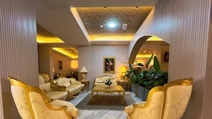 A luxurious living room with ornate gold furniture, a central coffee table, and a decorative ceiling.
