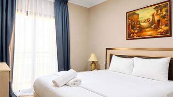 Een hotelkamer met een groot bed, een schilderij aan de muur en een raam met gordijnen.