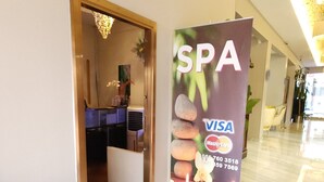 A spa area with a reception desk, a sign advertising spa services, and a marble floor.