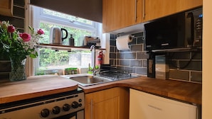 A kitchen with a stove, sink, and a Samsung microwave. There is a window with a view of greenery outside. - Woodland View by the Canal Hebden Bridge (Hebden Bridge)