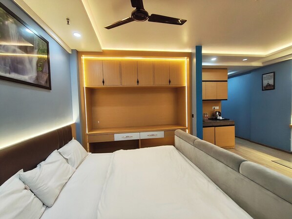 Una habitación de hotel moderna con una cama grande, armario empotrado y kitchenette.