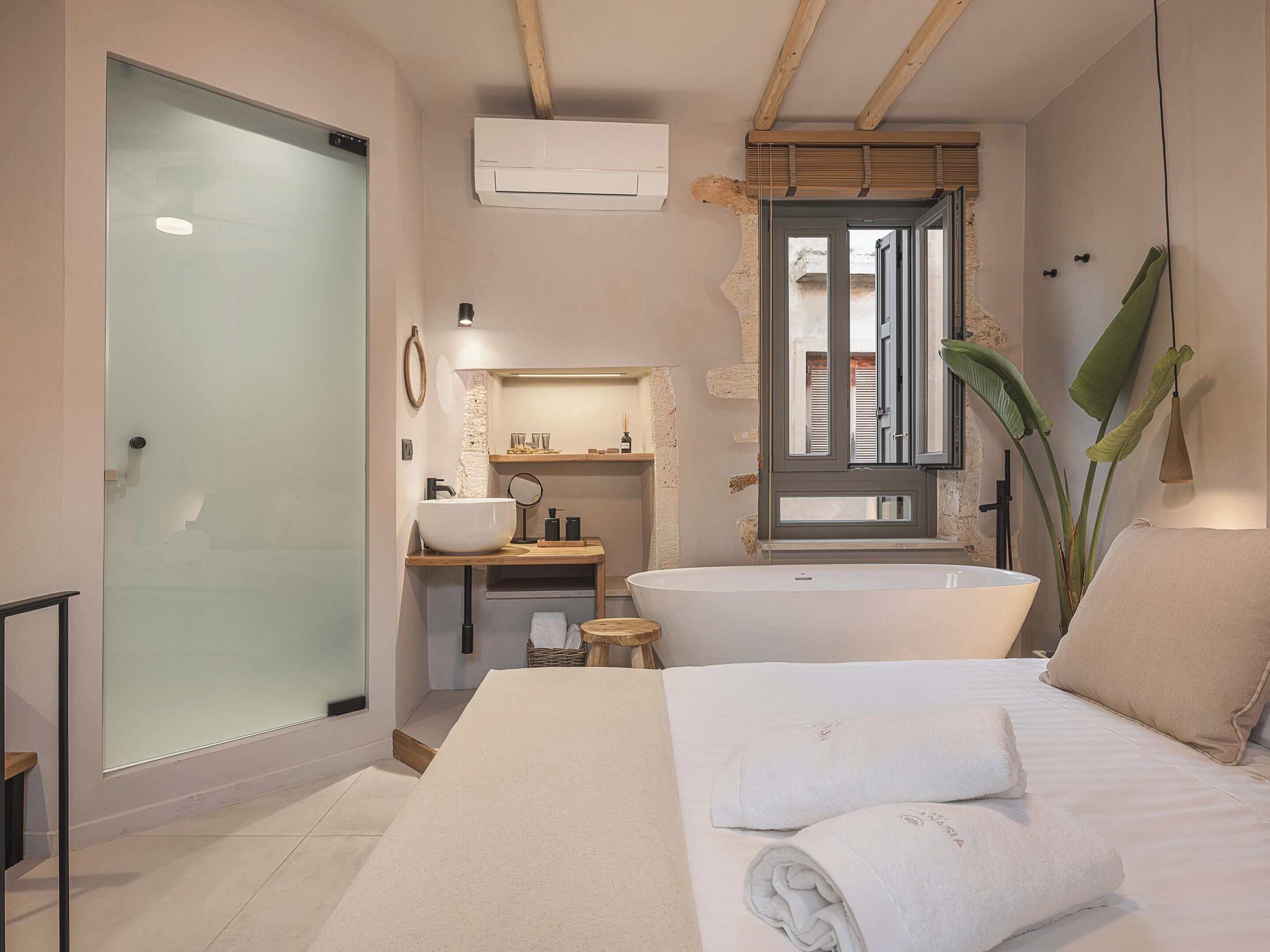 Un baño moderno con una bañera independiente, cabina de ducha con paredes de cristal y un tocador con un espejo grande.
