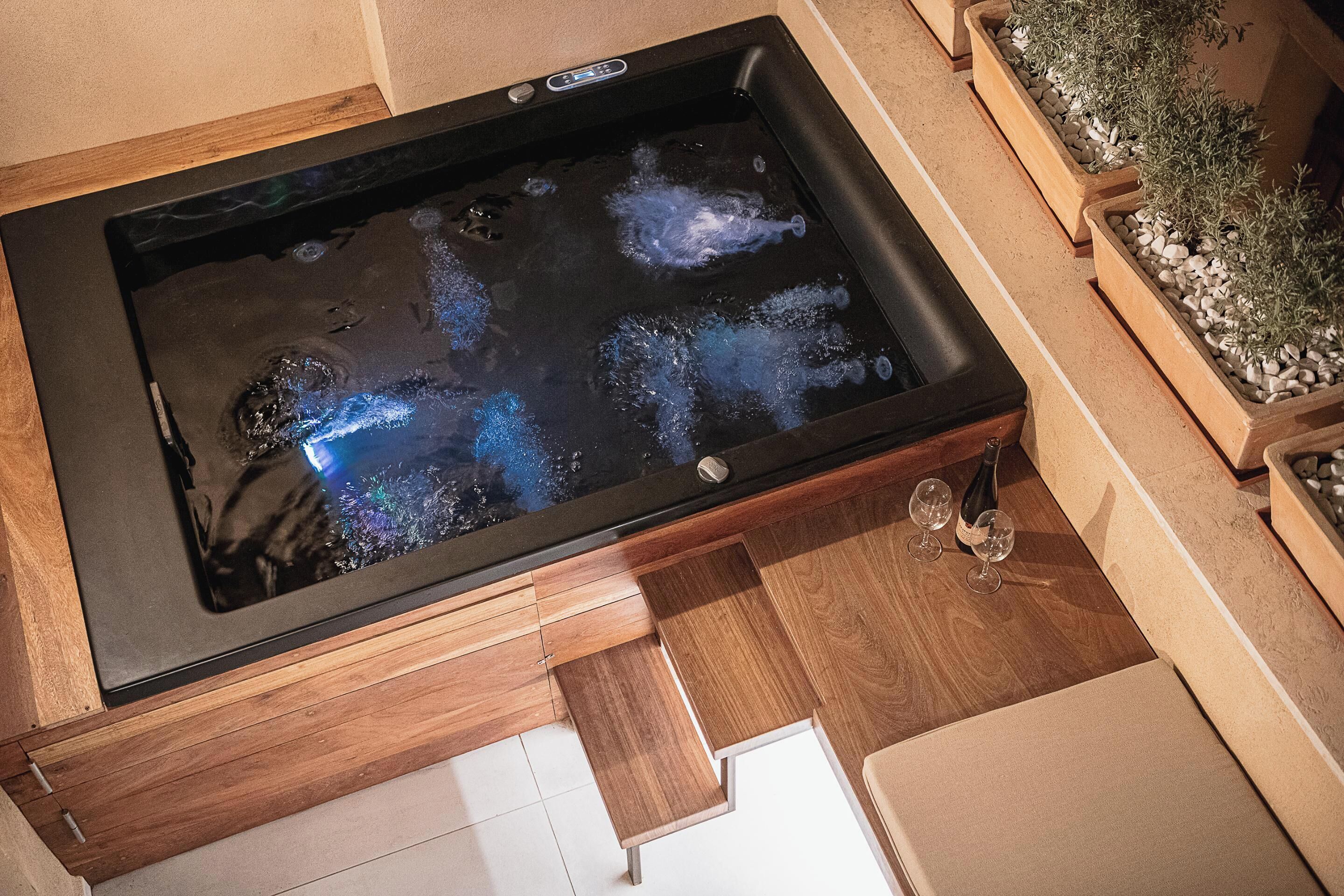 Ein Wellnessbereich mit Whirlpool, Holzschränken und Topfpflanzen.