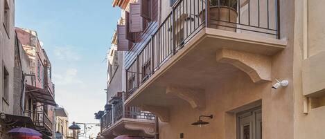 A narrow street lined with buildings featuring balconies, potted plants, and a sign for 'Boulevard'.