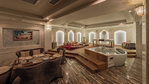 A luxurious spa area with a hot tub, seating area, and decorative windows. - Green City Resort (Baku)
