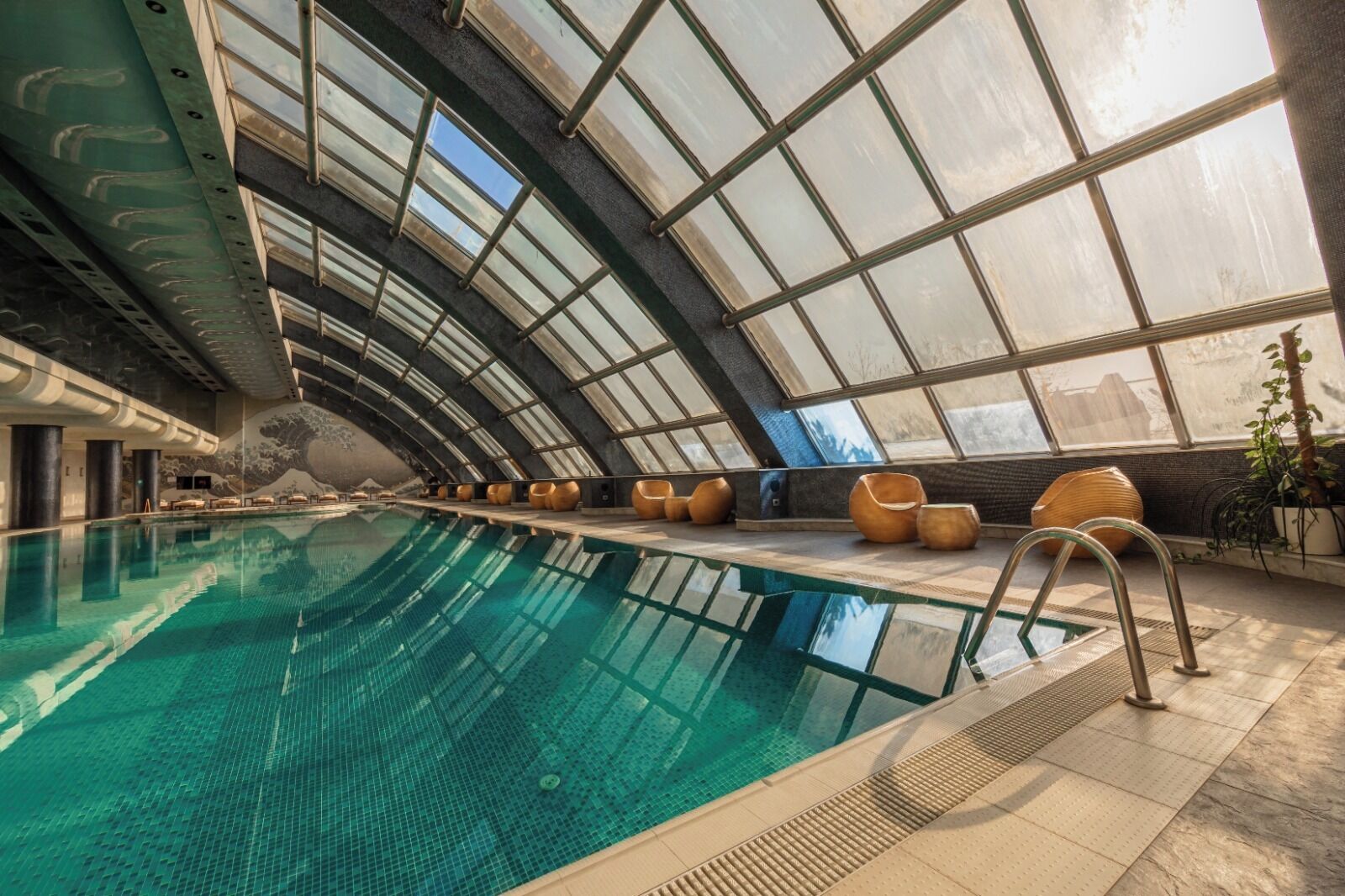 Een binnenzwembad met heldere glazen wanden, zitgedeeltes en een modern architectonisch ontwerp.