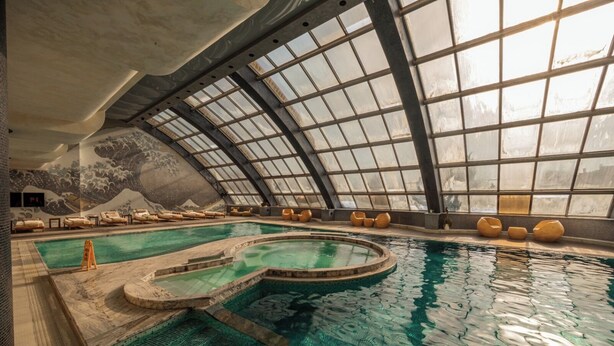 An indoor swimming pool with a unique design, including a curved section and a separate hot tub area. - Green City Resort (Baku)