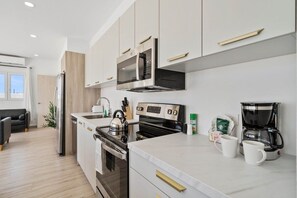 Een moderne keuken met roestvrijstalen apparatuur, een koffiezetapparaat en een waterkoker.