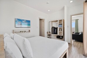 A bedroom with a bed, a painting, a wardrobe, and a bathroom visible through an open door.
