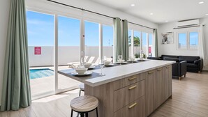 A modern kitchen with a large island, sliding glass doors, and a pool view.