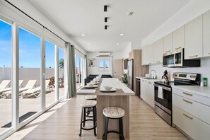 A modern kitchen with a central island, bar stools, and a dining area with a view.