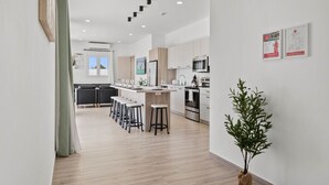 A modern kitchen with a central island, bar stools, and stainless steel appliances.