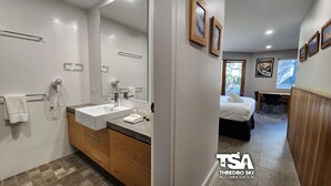 Un baño moderno con un espejo grande, un lavabo blanco y un secador de pelo.