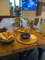 Une table en bois sur laquelle se trouvent un bol rempli de croissants, un bol noir et divers condiments.