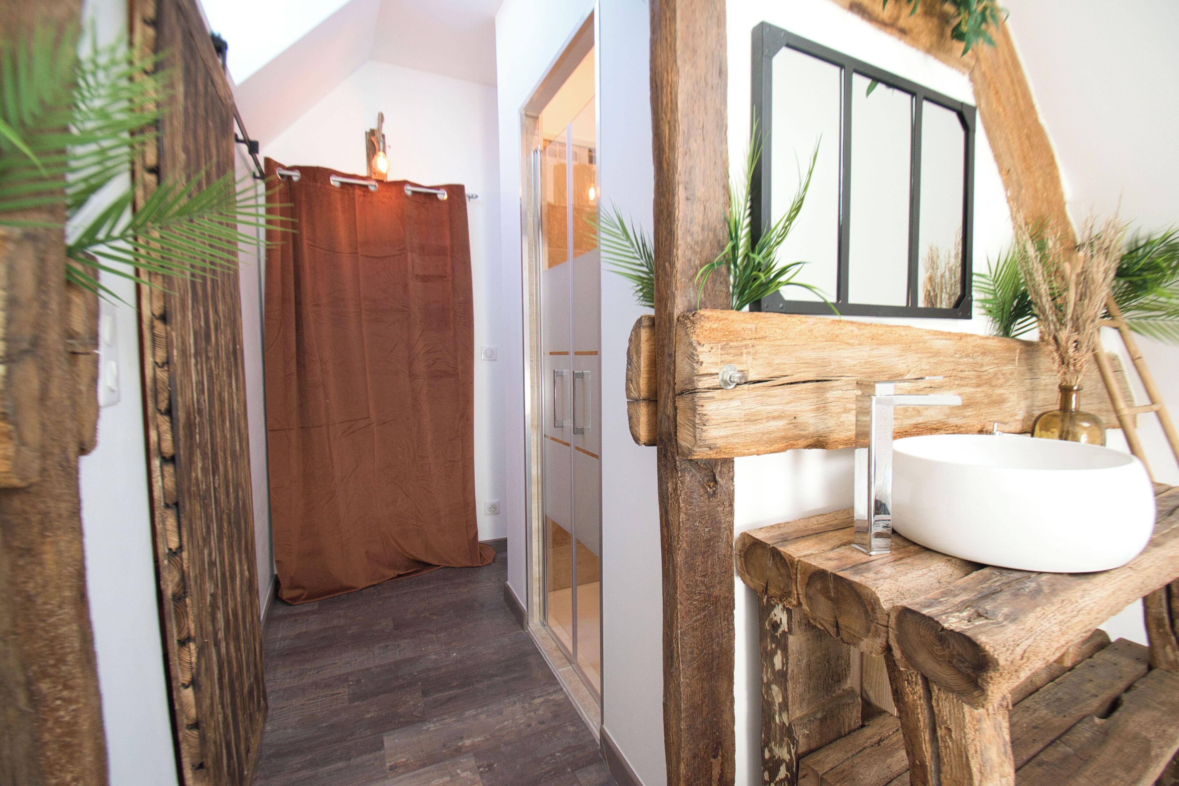 Un baño con un mueble de tocador de madera, un lavabo blanco y un espejo.