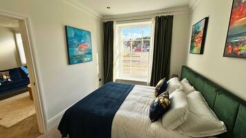 A bedroom with a bed, a window with curtains, and artwork on the walls.