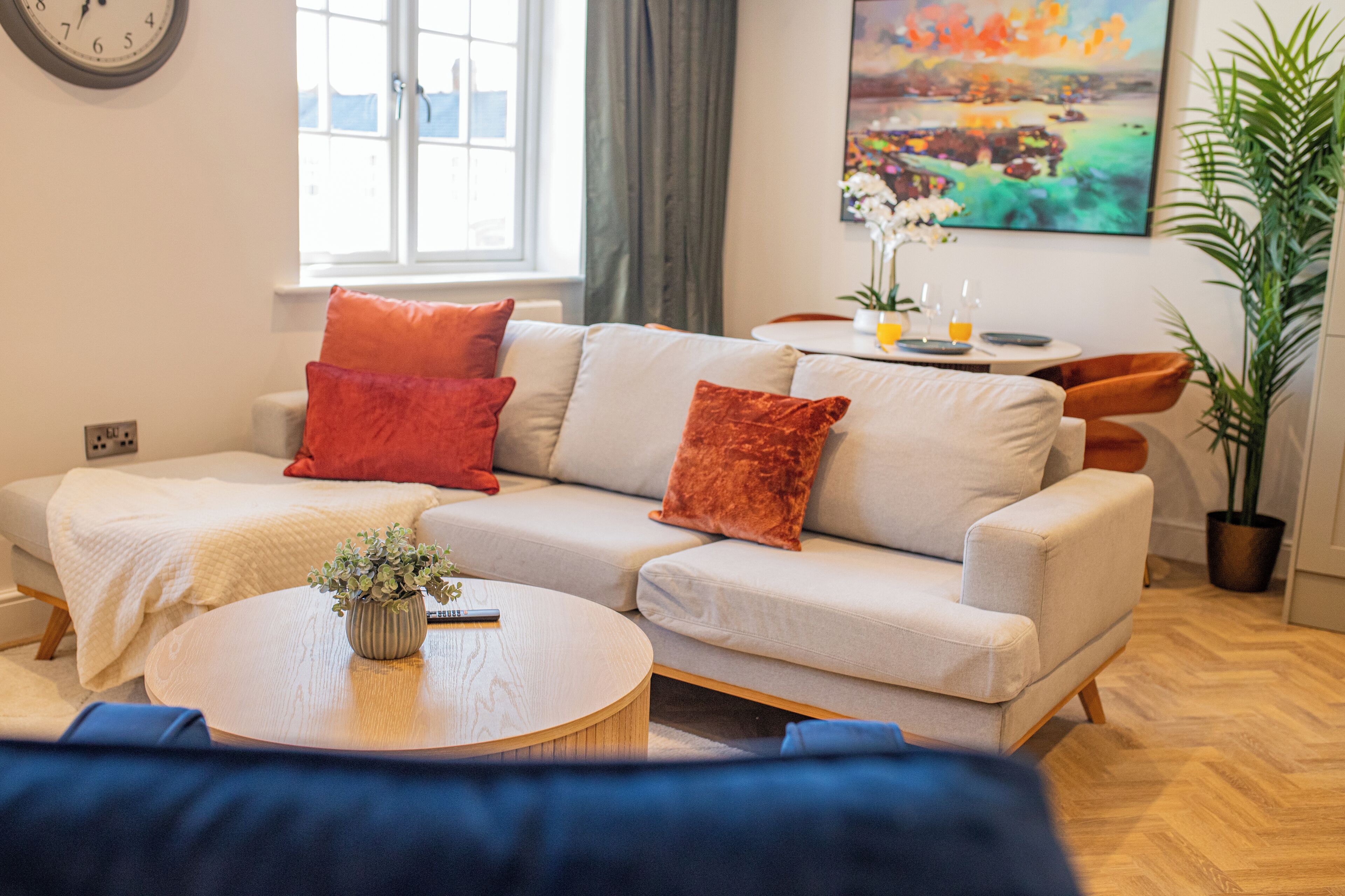 A living room with a sofa, a coffee table, and a painting on the wall.