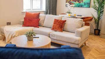 A living room with a sofa, a coffee table, and a painting on the wall.