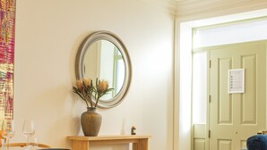 A dining area with a wooden table, chairs, a vase with flowers, and a mirror on the wall. - Charles Hope Salisbury Centre (Salisbury)