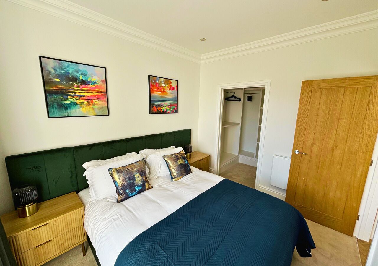 Un dormitorio con una cama, dos cuadros, una puerta de madera y un armario.