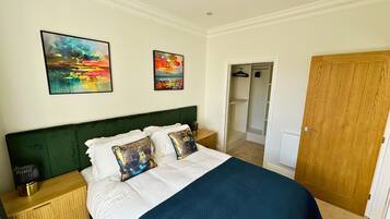 Un dormitorio con una cama, dos cuadros, una puerta de madera y un armario.