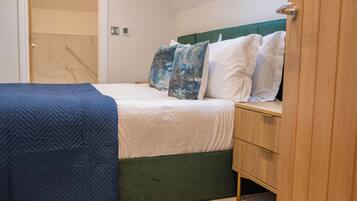 A bedroom with a bed, a wooden nightstand, and a green upholstered headboard.