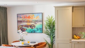 A modern living room with a sofa, a dining table with chairs, a potted plant, and a painting on the wall. - Charles Hope Salisbury Centre (Salisbury)