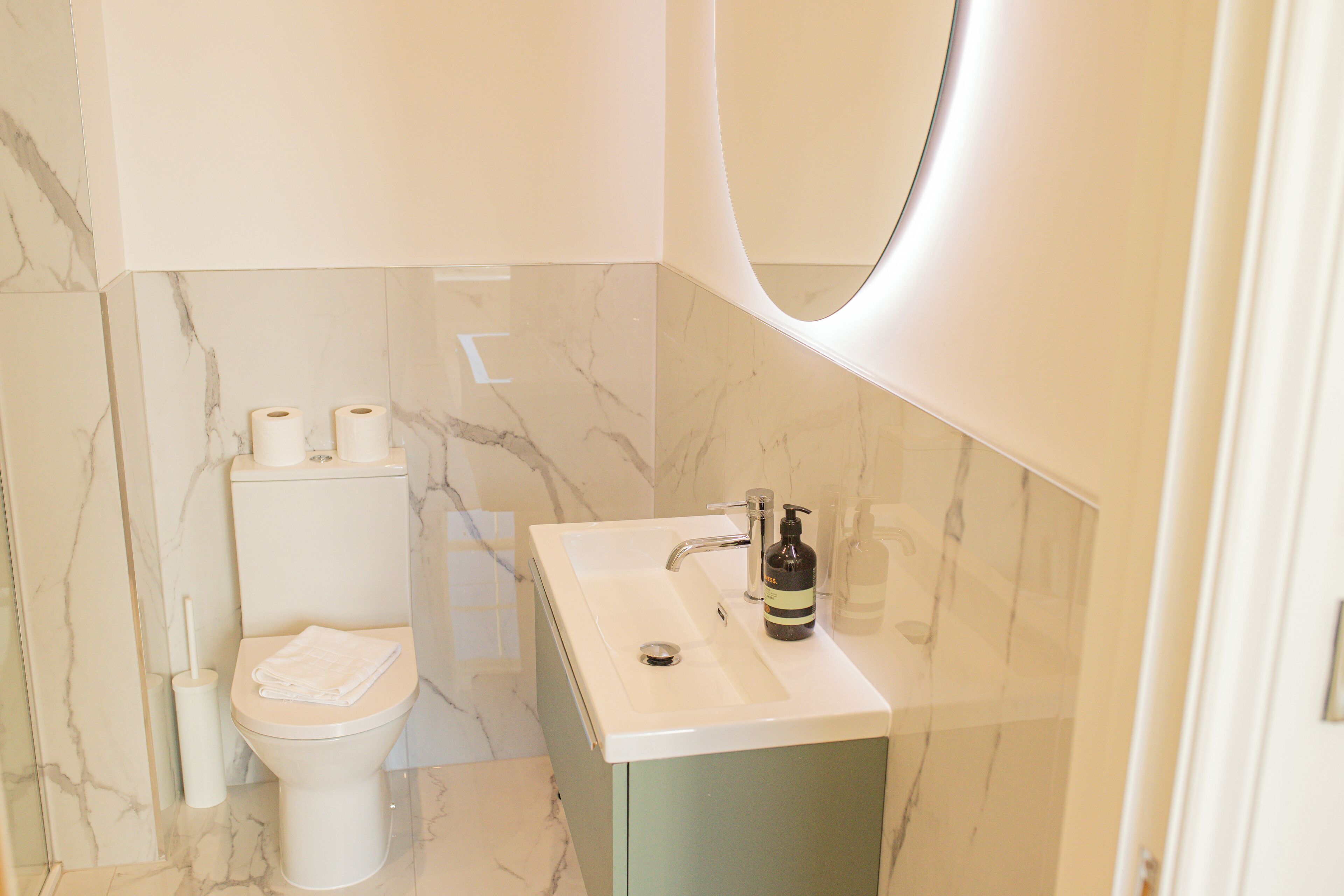 Un baño moderno con inodoro, lavamanos y espejo.