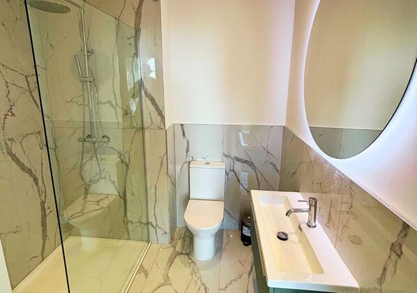 A modern bathroom with a glass-enclosed shower, a toilet, and a sink with a large mirror. - Charles Hope Salisbury Centre (Salisbury)