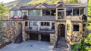 Une maison à deux étages avec une façade en pierre, de nombreux balcons et de grandes fenêtres.