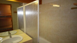 Ein Badezimmer mit zwei Waschbecken, einem Spiegel und einer Duschkabine.