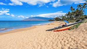 A beach with a clear sky, palm trees, and a mountain in the background. - Kamaole Beach 1 Condo at Kihei Ali'i Kai (Kihei)