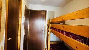 A narrow hallway with wooden bunk beds on one side and a door at the end. - 150m from ski slopes, 4th floor, view ski slopes, balcony, tv, ski locker, 24m², Les Saisies (Les Saisies)