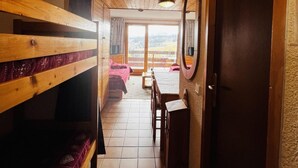 A narrow corridor with bunk beds on the left, a wooden desk and chair in the center, and a door on the right. - 150m from ski slopes, 4th floor, view ski slopes, balcony, tv, ski locker, 24m², Les Saisies (Les Saisies)