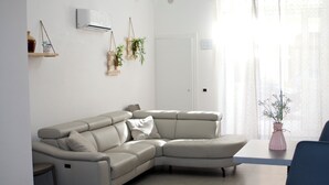 En moderne stue med en hjørnesofa, et spisebord og en potteplante.