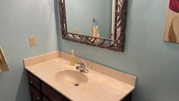 A bathroom with a beige sink, dark wooden cabinets, a mirror with a decorative frame, and a towel hanging on the wall.