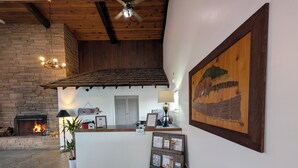 A reception area with a fireplace, a desk, a framed picture, and a ceiling fan.