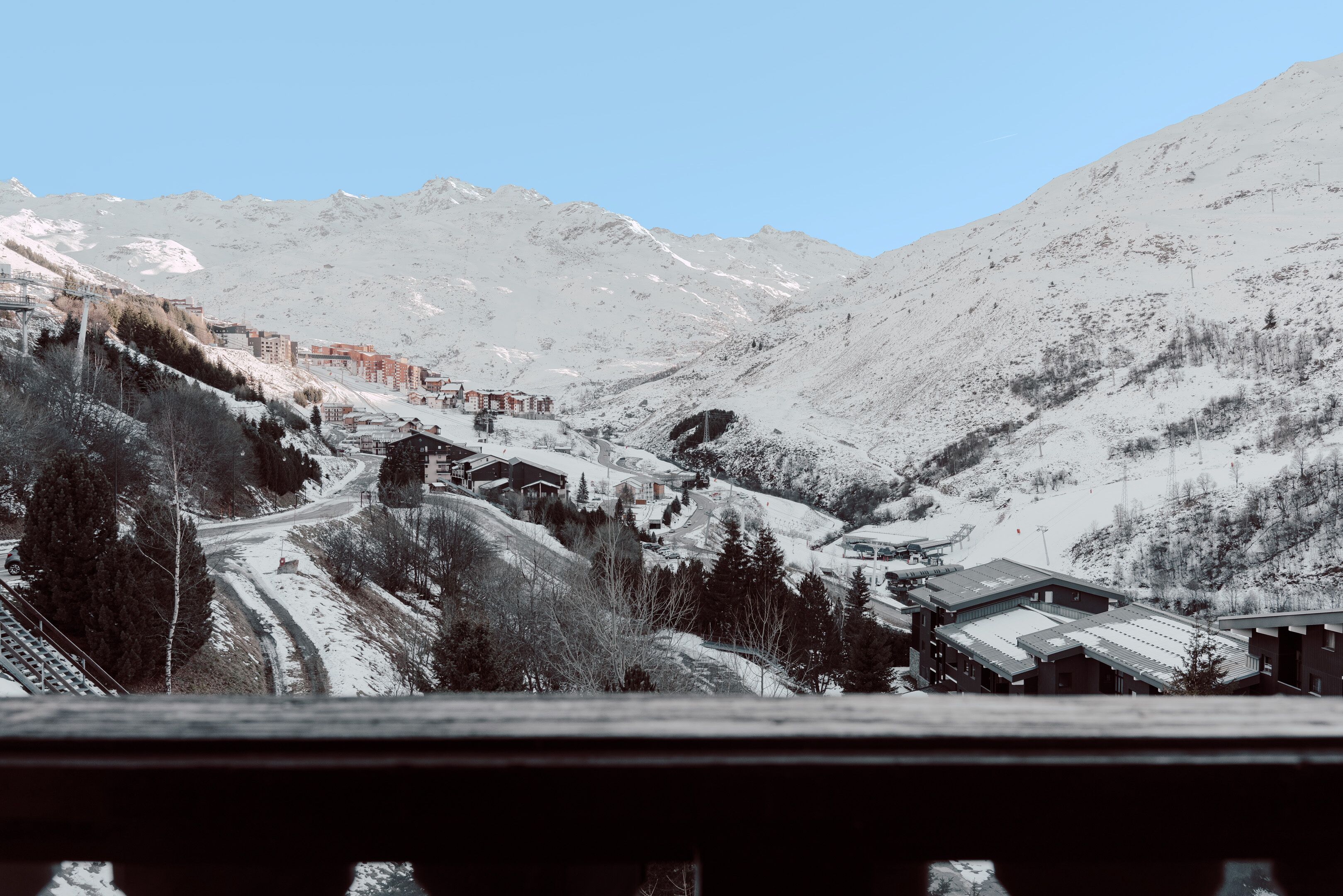 Un pueblo cubierto de nieve con edificios y un telesilla.