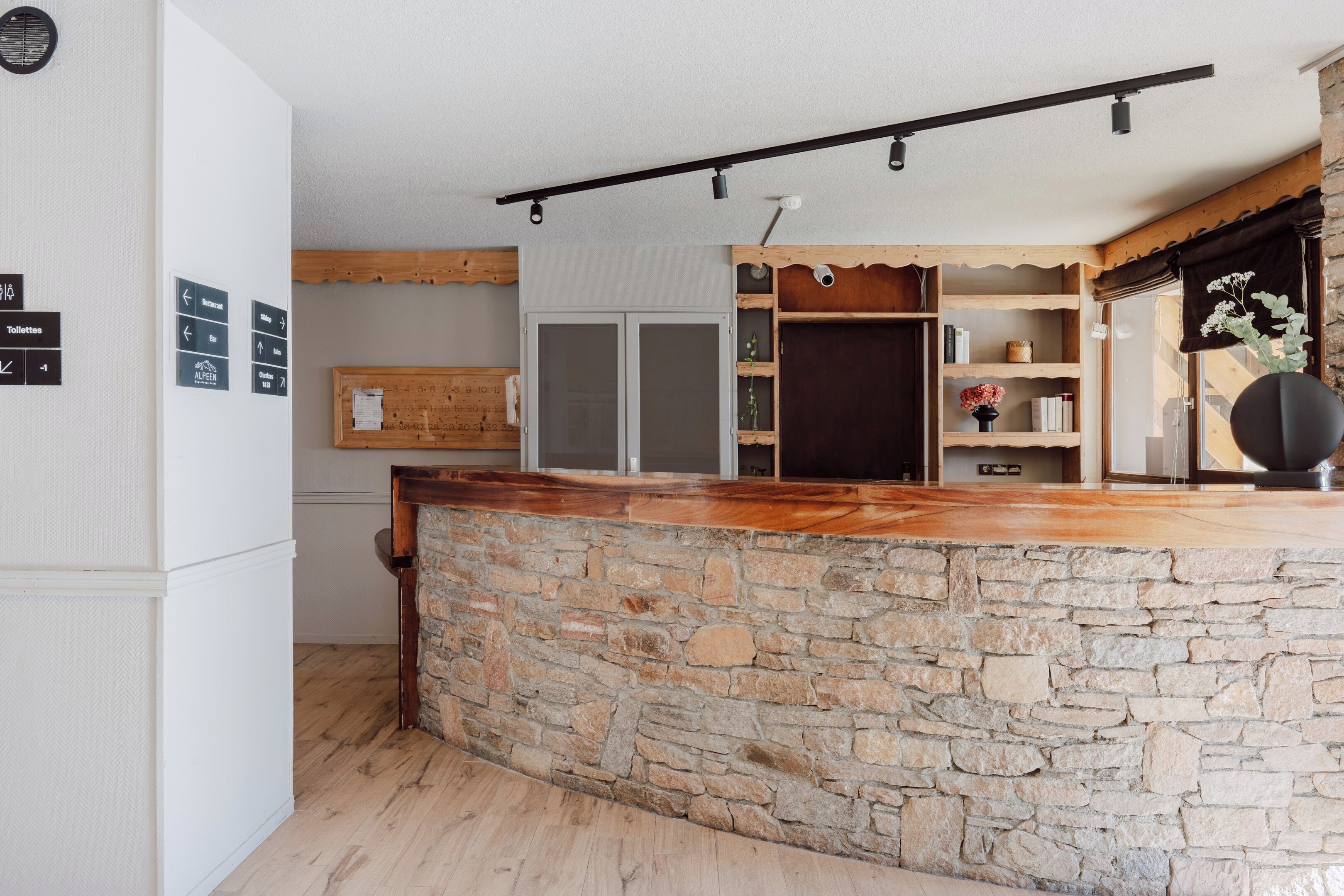 A kitchen with a stone counter, wooden shelves, and a white refrigerator.