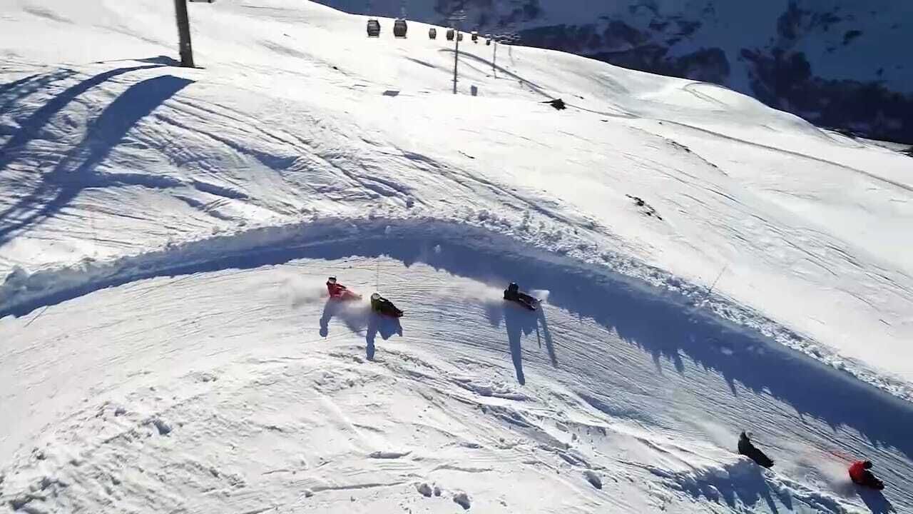 A snowy ski slope with skiers and a ski lift in the background.