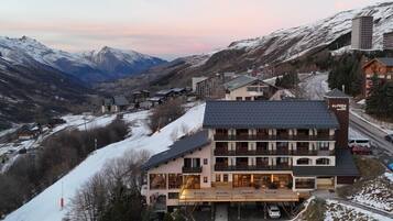 A hotel with multiple floors, a balcony, and a view of snow-covered mountains.