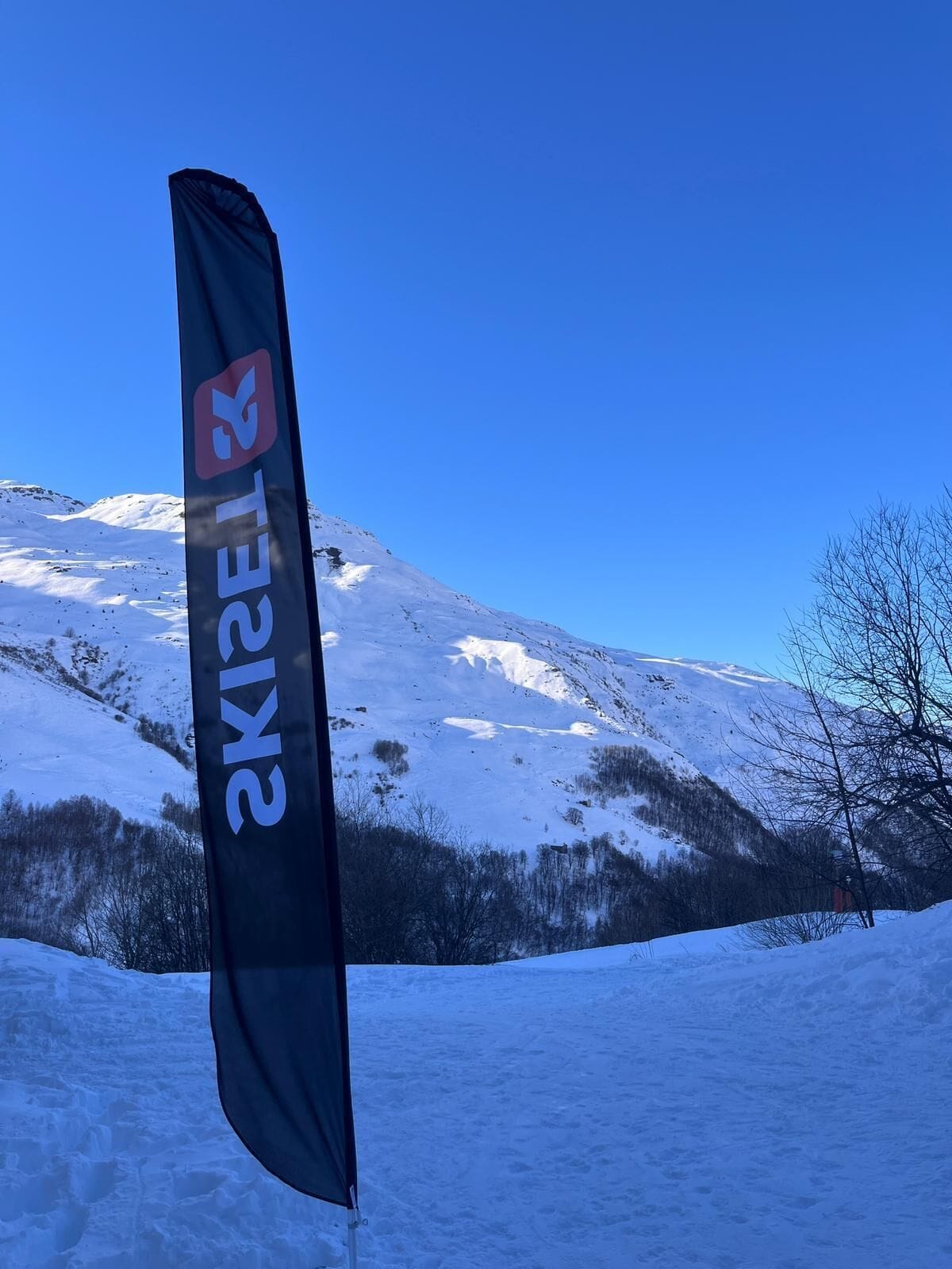A flag with the text "ELKEFEL" in a mountainous landscape.