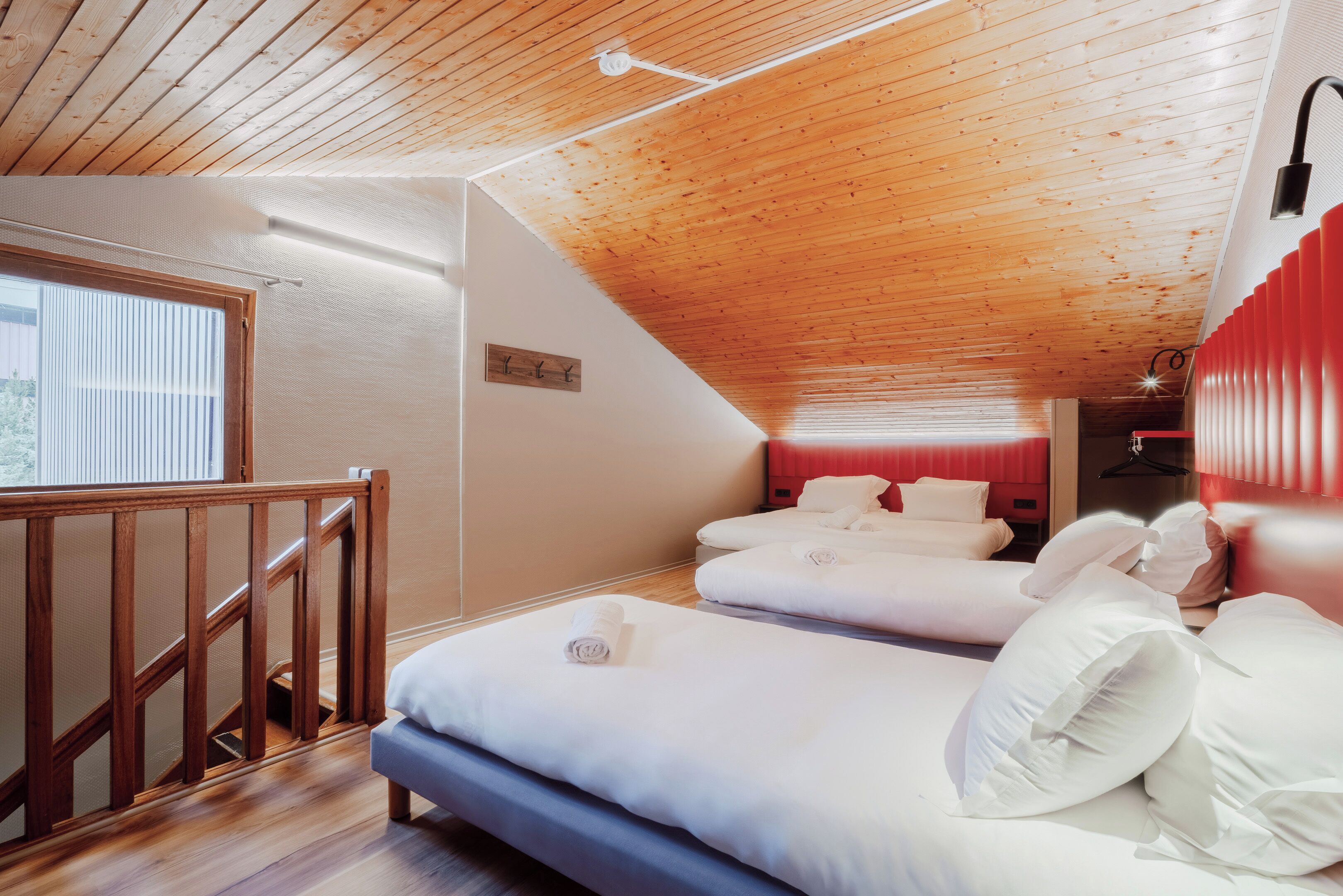 Un dormitorio con dos camas, techo de madera y una ventana con persianas.