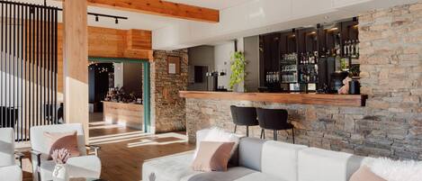 A modern living room with a large sofa, a coffee table, and a bar area with shelves of bottles.