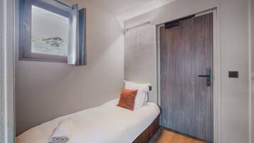 Un dormitorio con cama, ventana con vistas, puerta y una toalla sobre la cama.