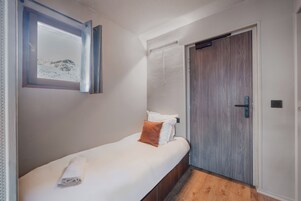 A bedroom with a bed, a window with a view, a door, and a towel on the bed.
