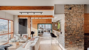 A spacious living area with a stone wall, wooden beams, and modern furniture. - Alpeen Hotel (Les Belleville)