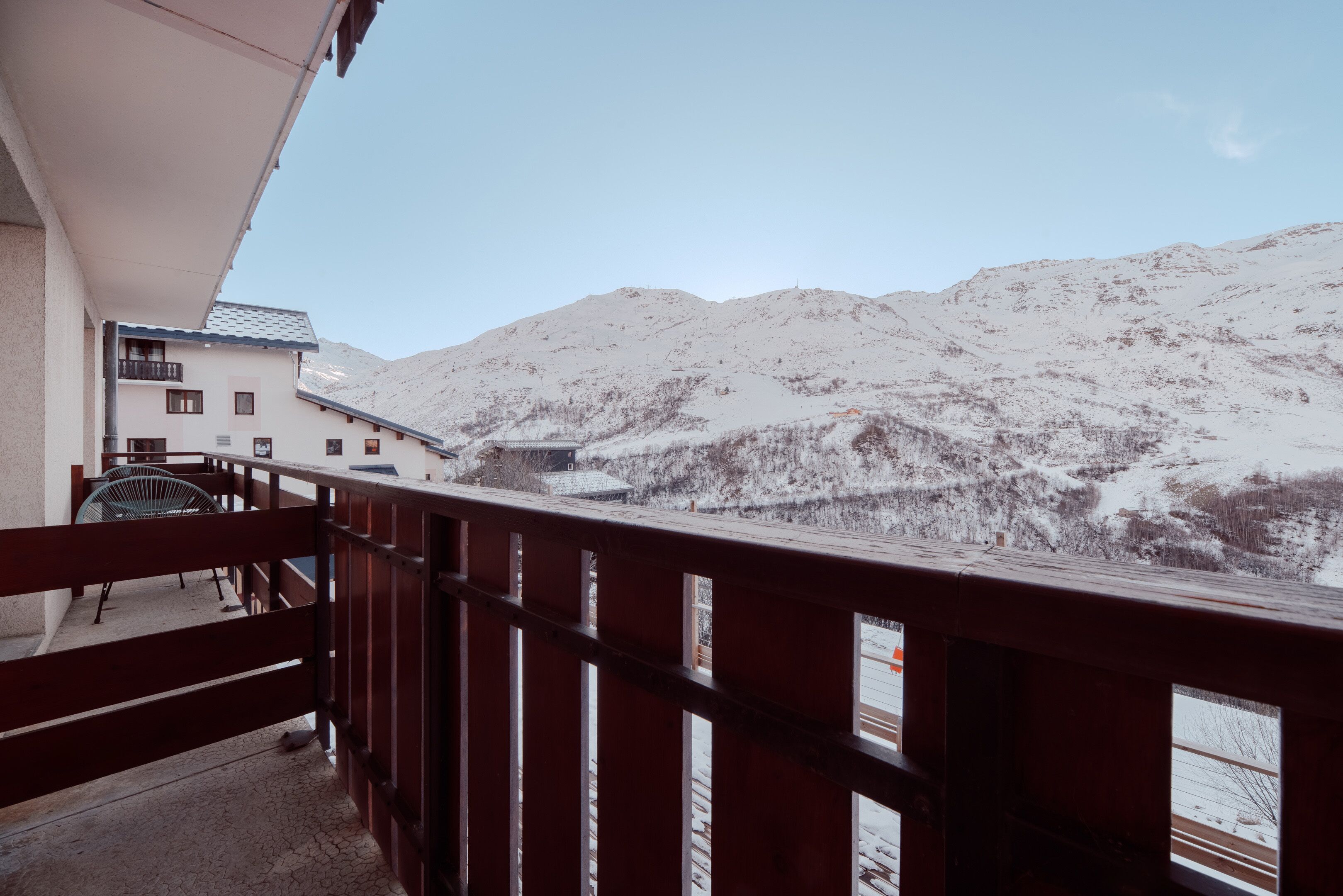 En balkon med gelænder af træ, der ud til et sneklædt bjerg.